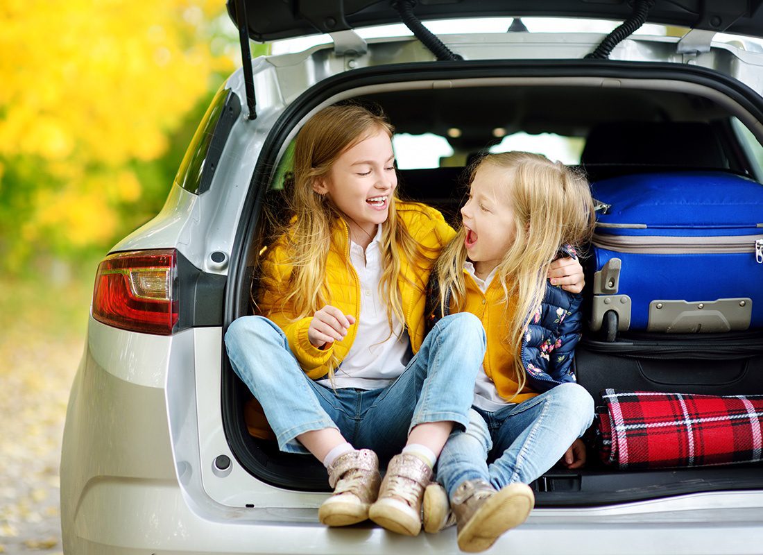 Personal Insurance - Happy Girls Sitting in the Back of a Car During a Trip